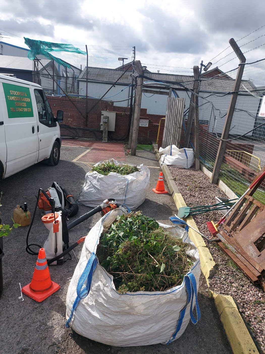 Collected green waste in bulk bags beside grounds maintenance equipment and the team van